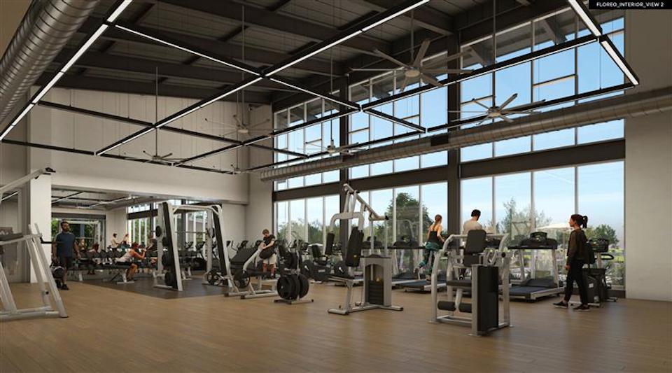 A group of people working out in a large room with large windows.